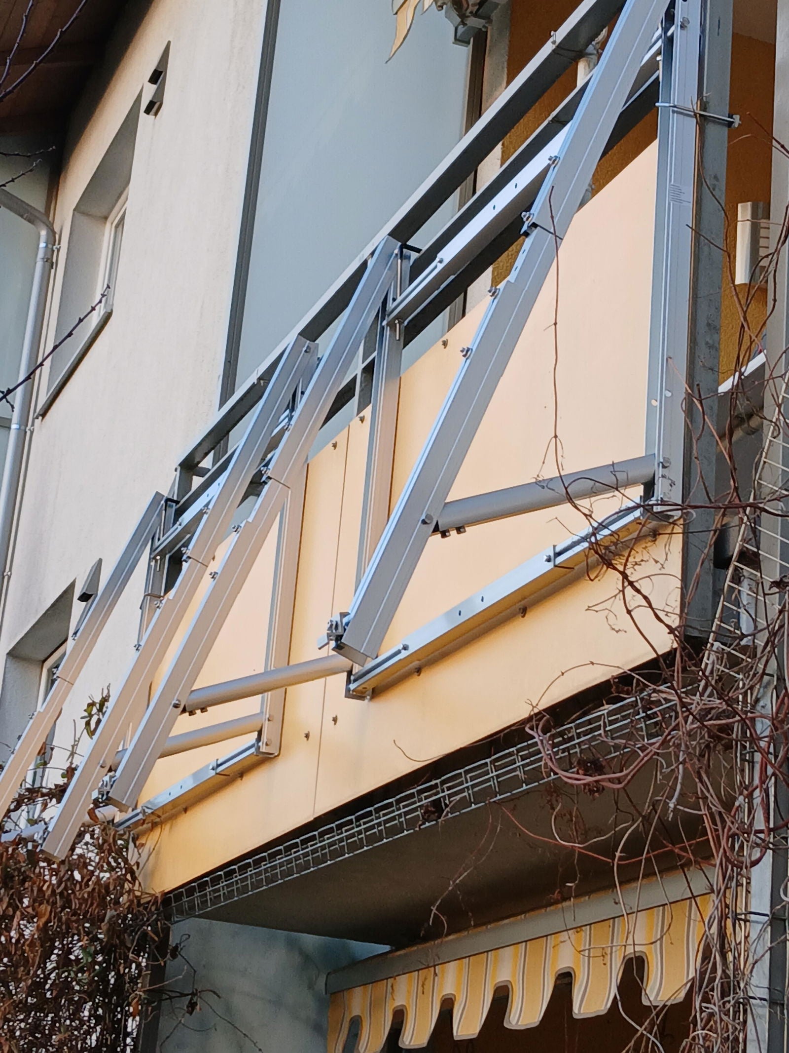 Aluminium-Halterungen an einer Plattenbrüstung: die Klemmung sitzt am oberen Rahmenprofil, nicht auf der Platte