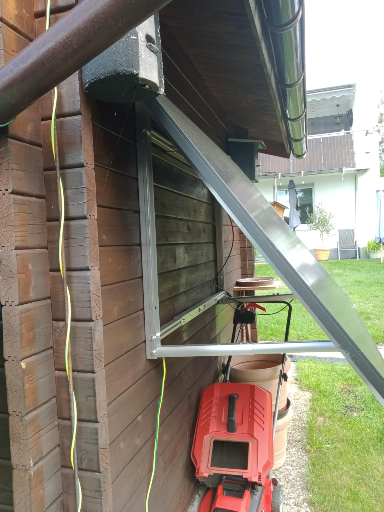 Balkonkraftwerk mit Wandhalterung an der Holzwand eines Gartenhauses montiert, Modul angewinkelt nach vorn